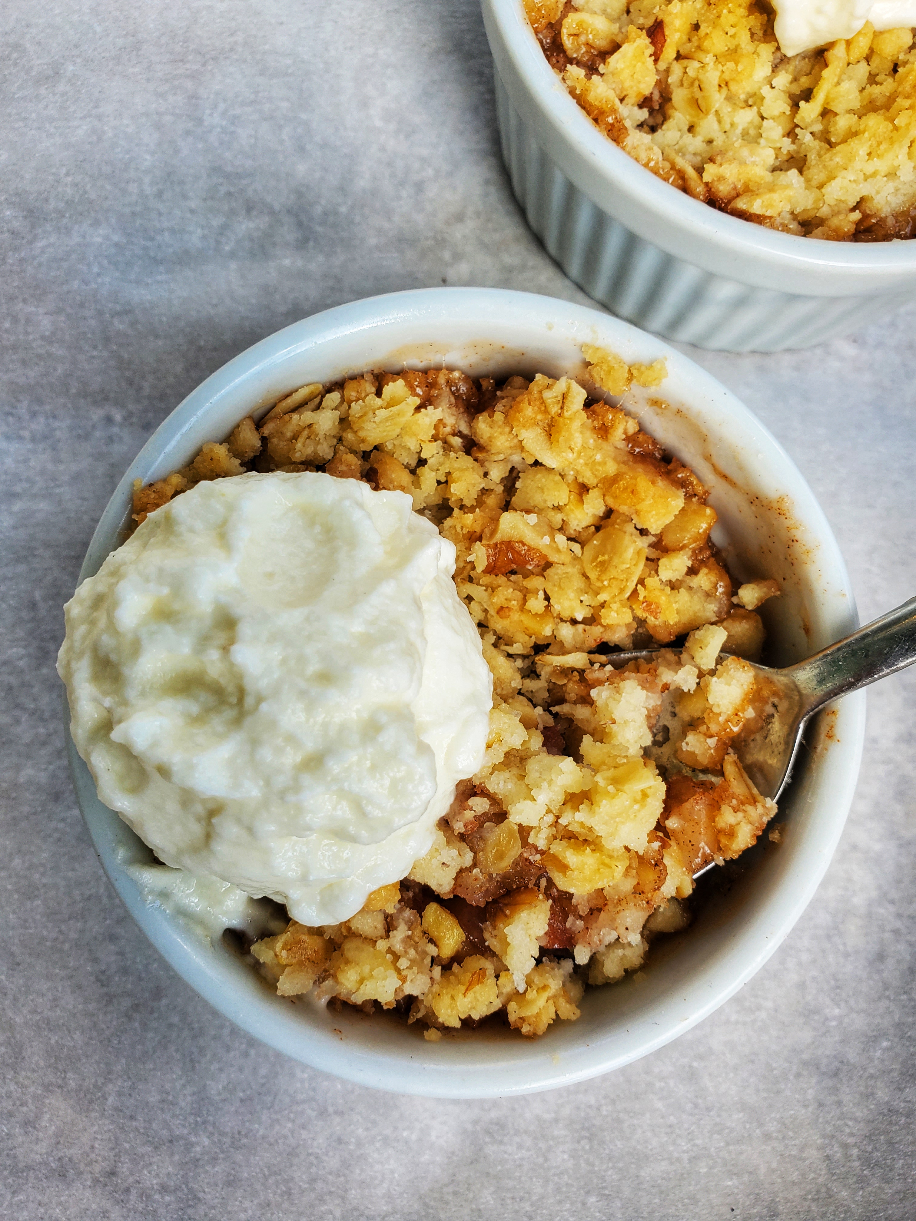 Apple crumble in a ramekin with a dollop of whipped cream