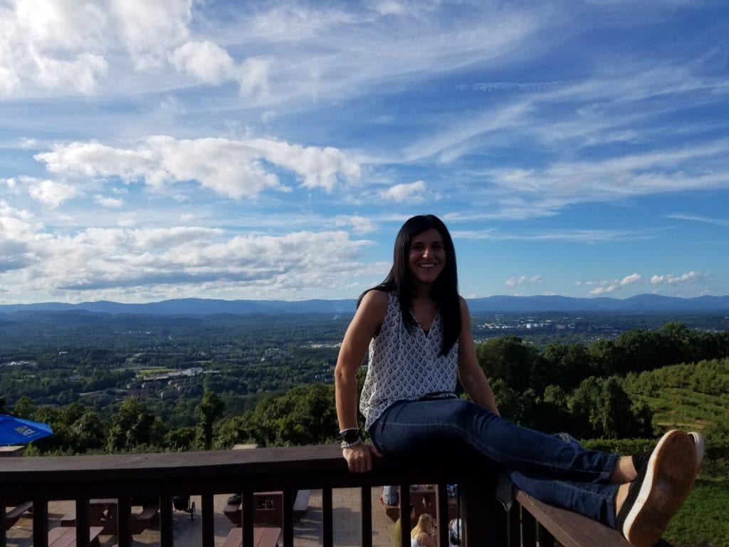 Me sitting on a ledge at a brewery overlooking the Blue Ridge Mountains