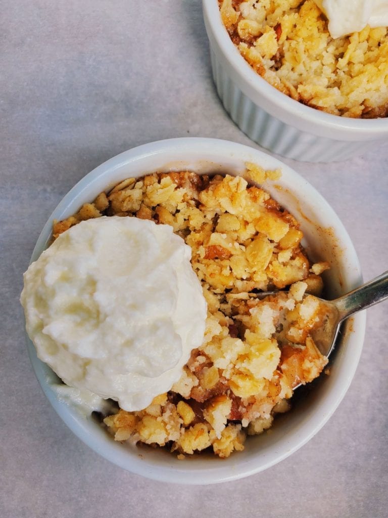 apple crumble in a ramekin with a dollop of whipped cream