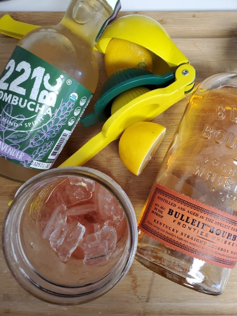 Kombucha, lemon in a lemon juicer, bourbon, and a glass
