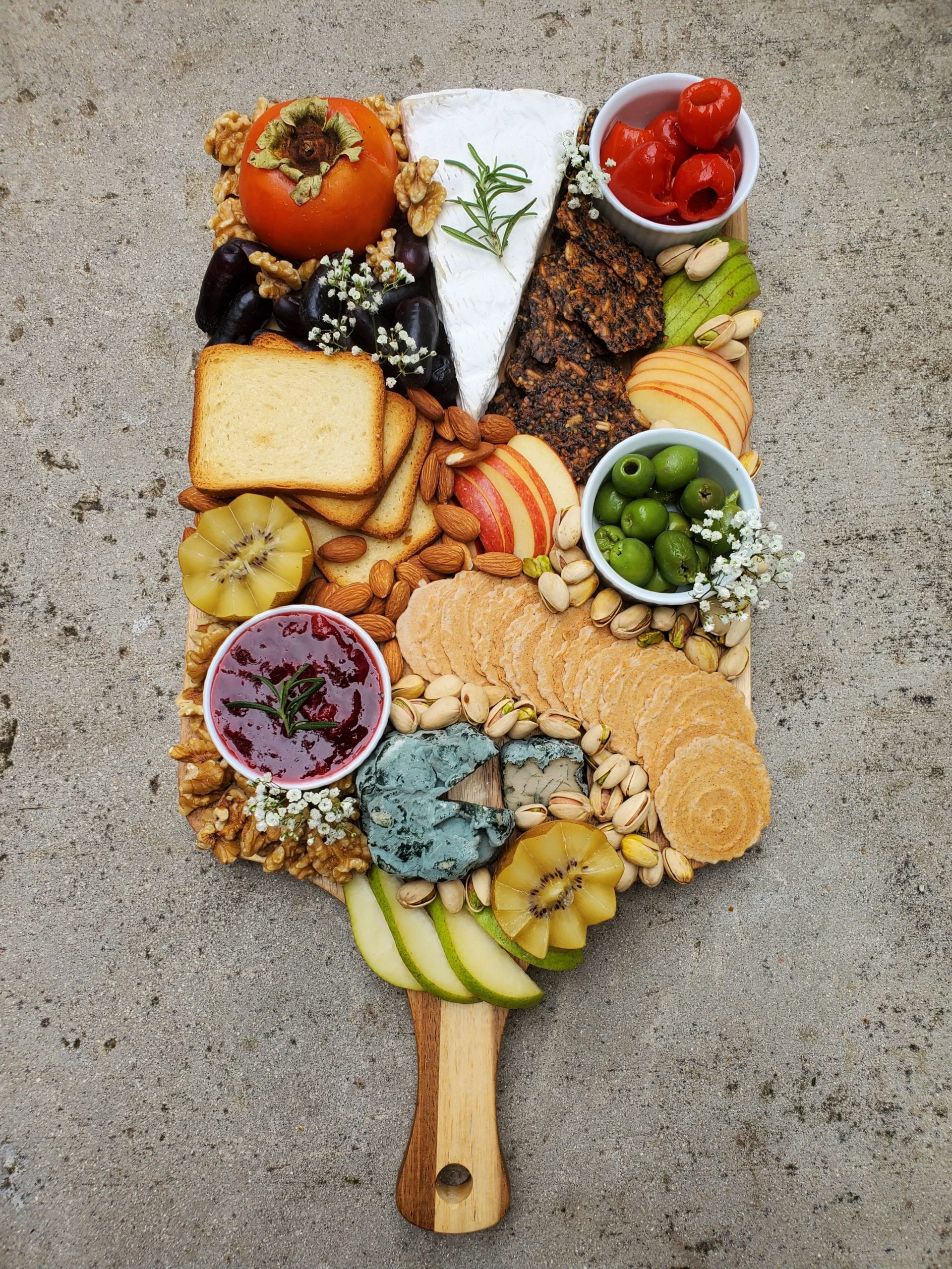 cheeseboard with a variety of cheese, nuts, and fruit