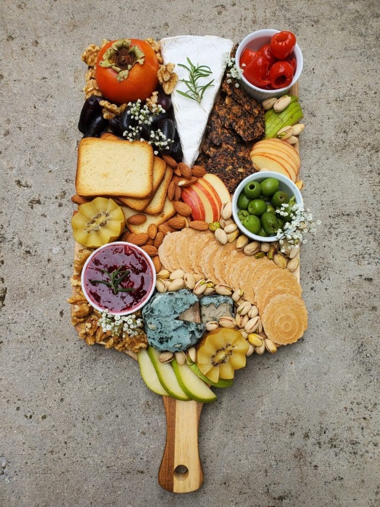 Cheeseboard with a variety of cheeses, fruits, jams, and appetizers