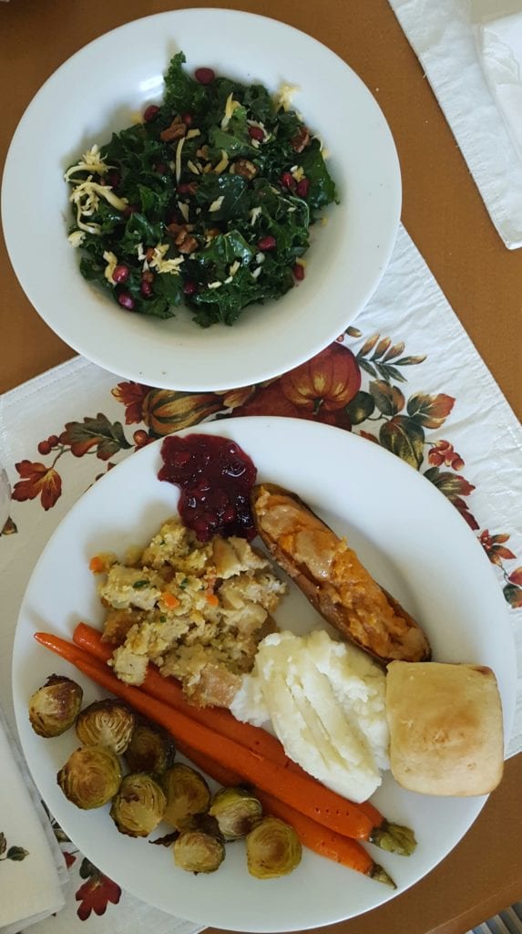 Thanksgiving meal with sweet potato, kale sale, stuffing, carrots, mashed potatoes, homemade cranberry sauce, brussels and a roll