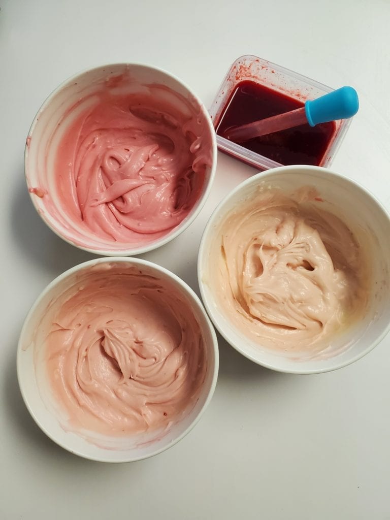 three bowls of cream cheese frosting in different shades of pink
