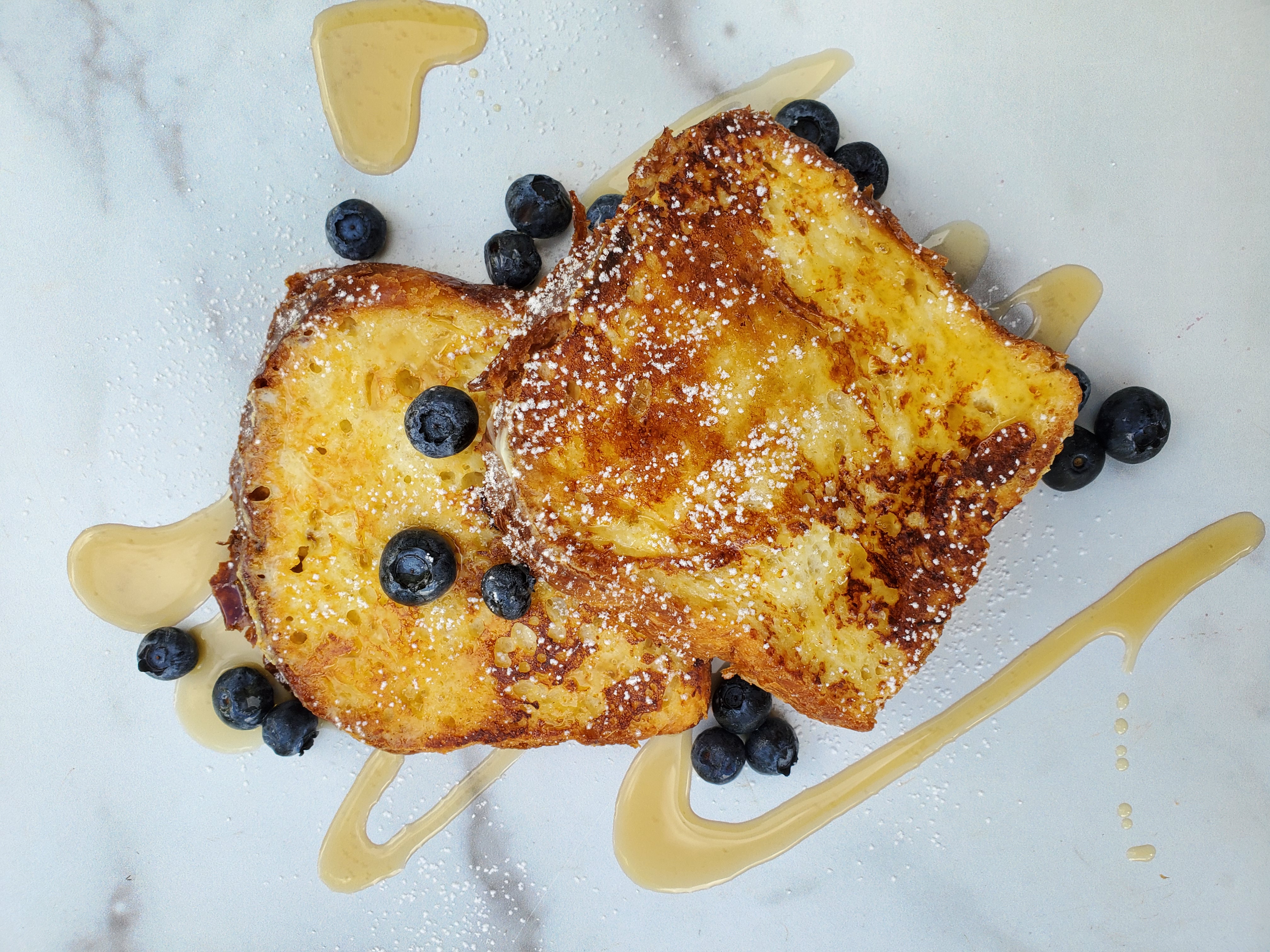 2 slices of French toast with blueberries and a drizzle of maple syrup