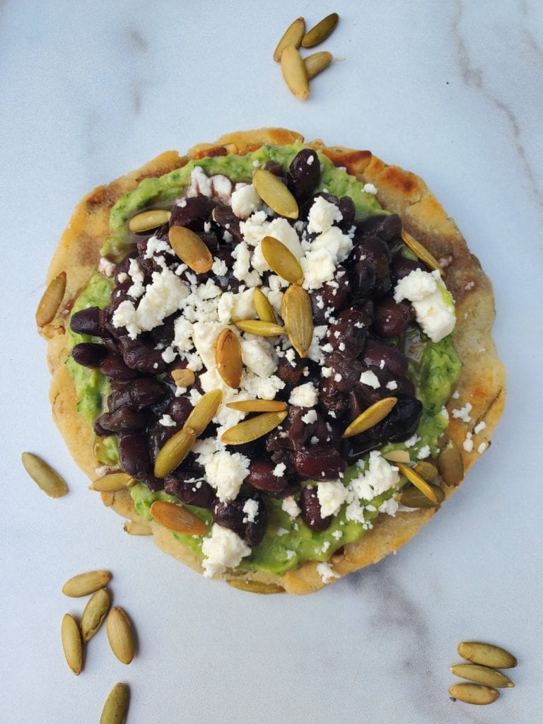 tortilla with black beans guacamole, feta cheese, and pumpkin seeds