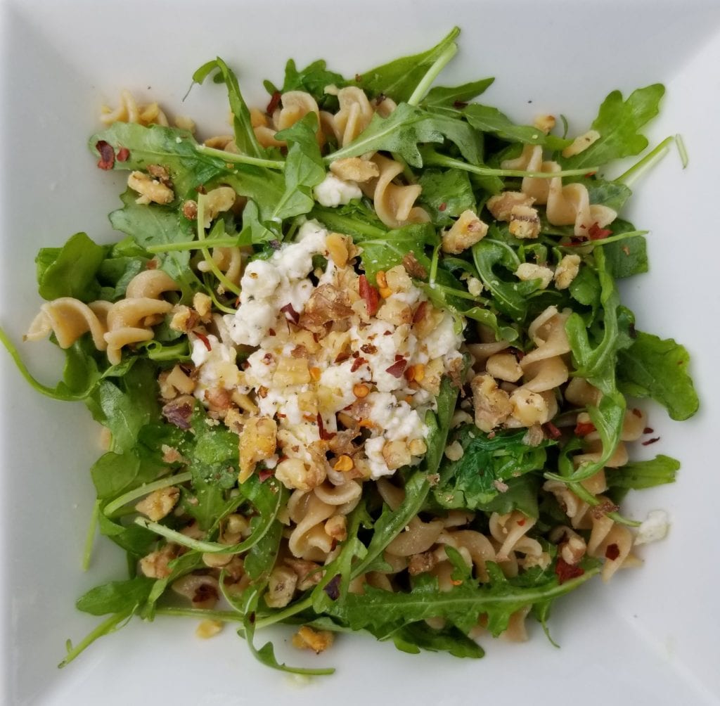 plate of pasta with arugula and feta and walnuts