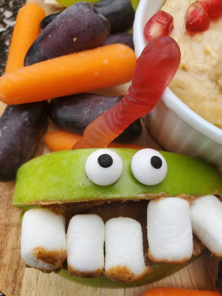 two apple slices with marshmallows in between to look like a monster with googly eyes