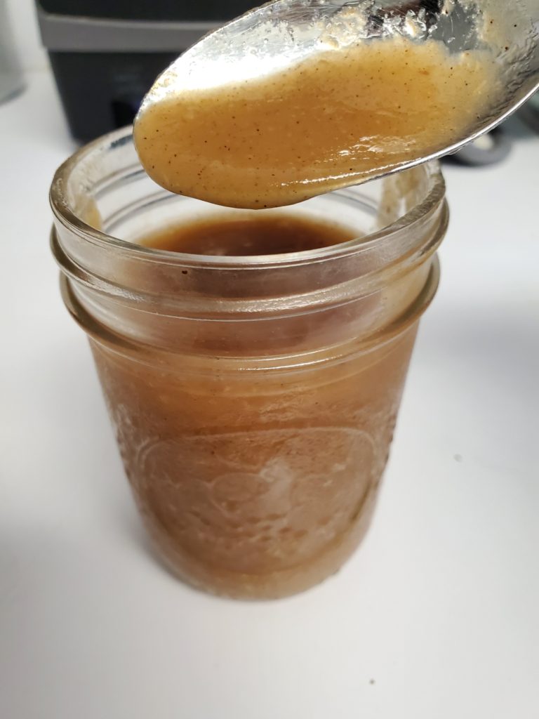 Mason jar with a spoon of the the homemade applesauce