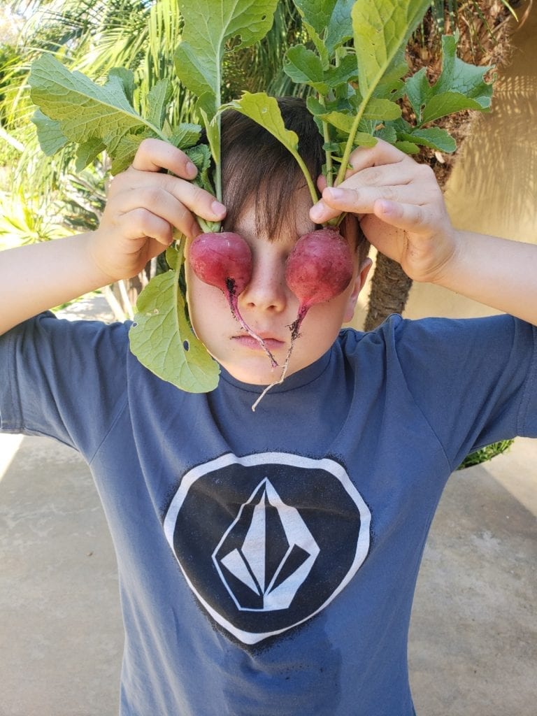 kid with radishes covering his eyes