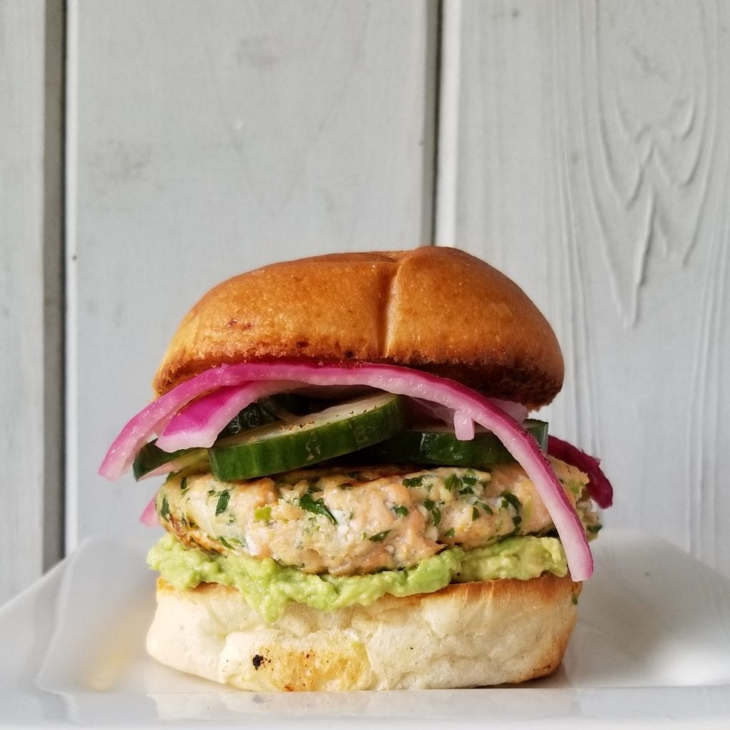 salmon goddess burger with guacamole and pickled red onions