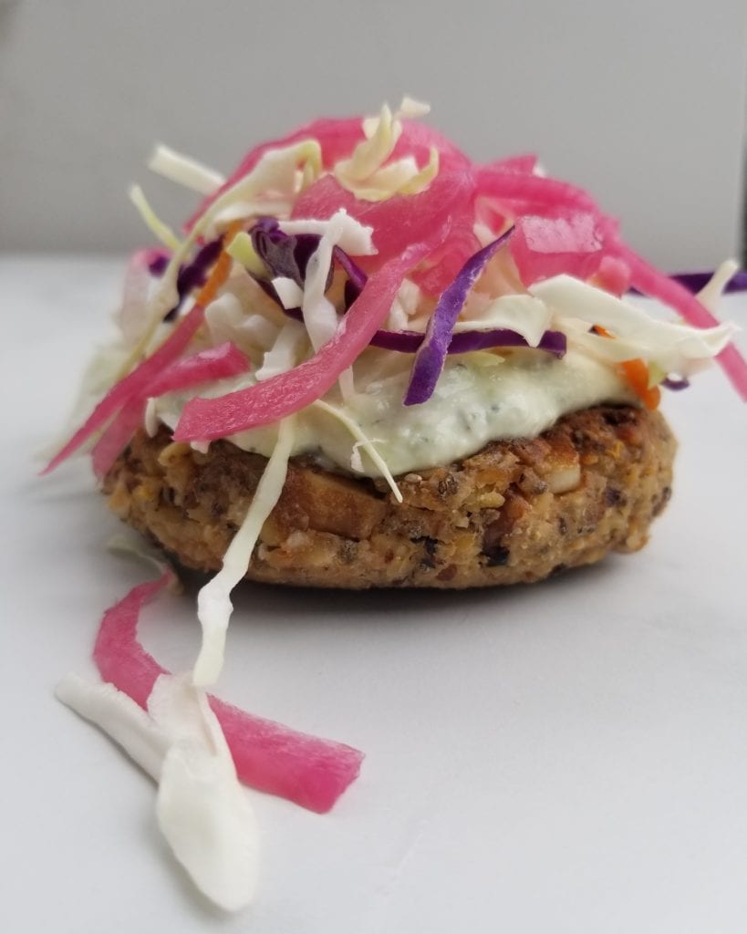 veggie burger with coleslaw on top and pickled red onions