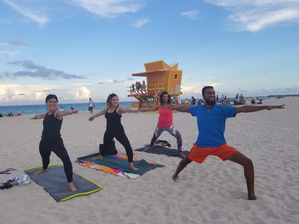 people doing yoga on the beach in warrior one pose