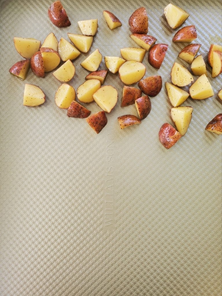 Sheet pan with cut up potatoes at the top third of the pan