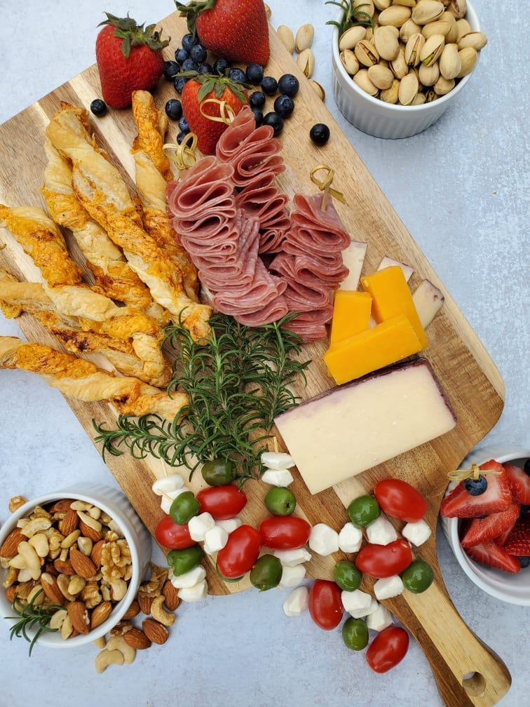 cheeseboard with a variety of cheeses, salami, and fruit and nuts