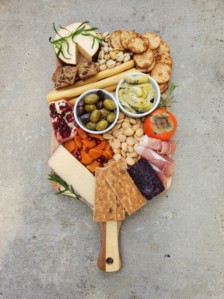 Cheeseboard with different cheeses, fruit, and veggies