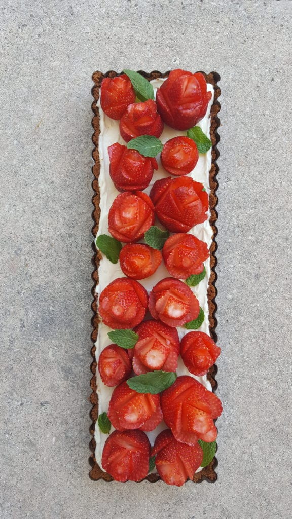 strawberries cut to look like roses on top of a cheesecake tart