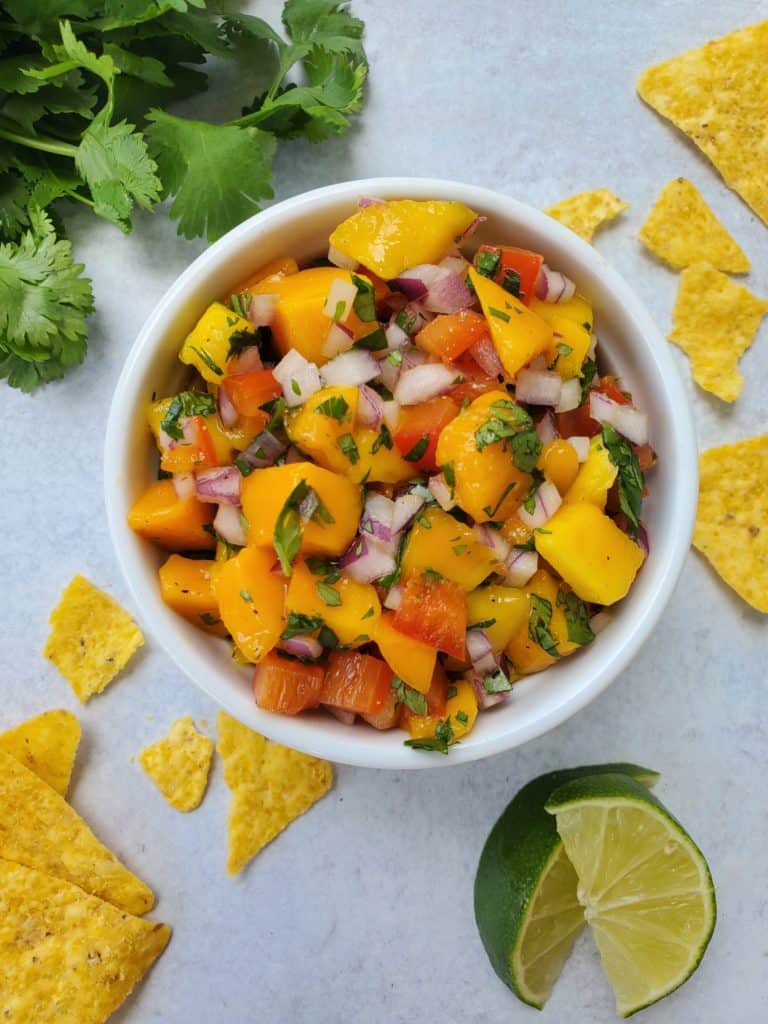 Mango salsa - mango, red pepper, red onion, cilantro in a ramekin with chips and salsa