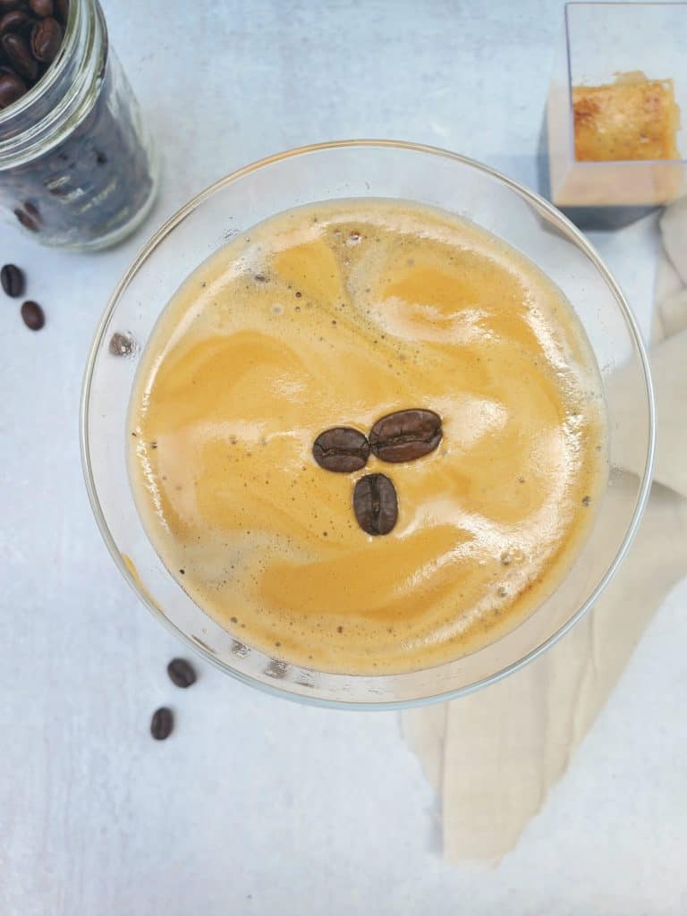 Overhead shot of the espresso martini with the foam on top and three espresso beans