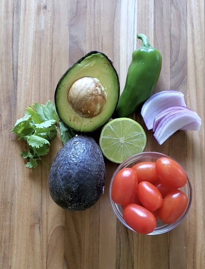 Ingredients for guacamole - avocado, jalapeno, red onion, tomato, cilantro, & llime juice