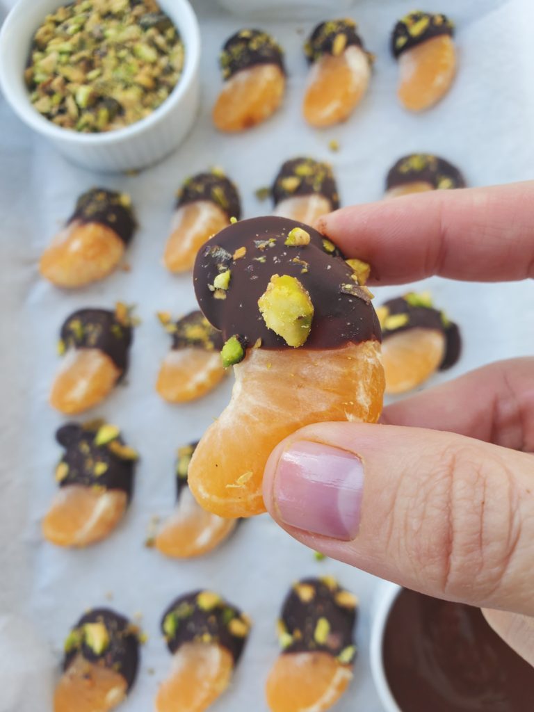 Hand holding a dark chocolate dipped mandarin close-up