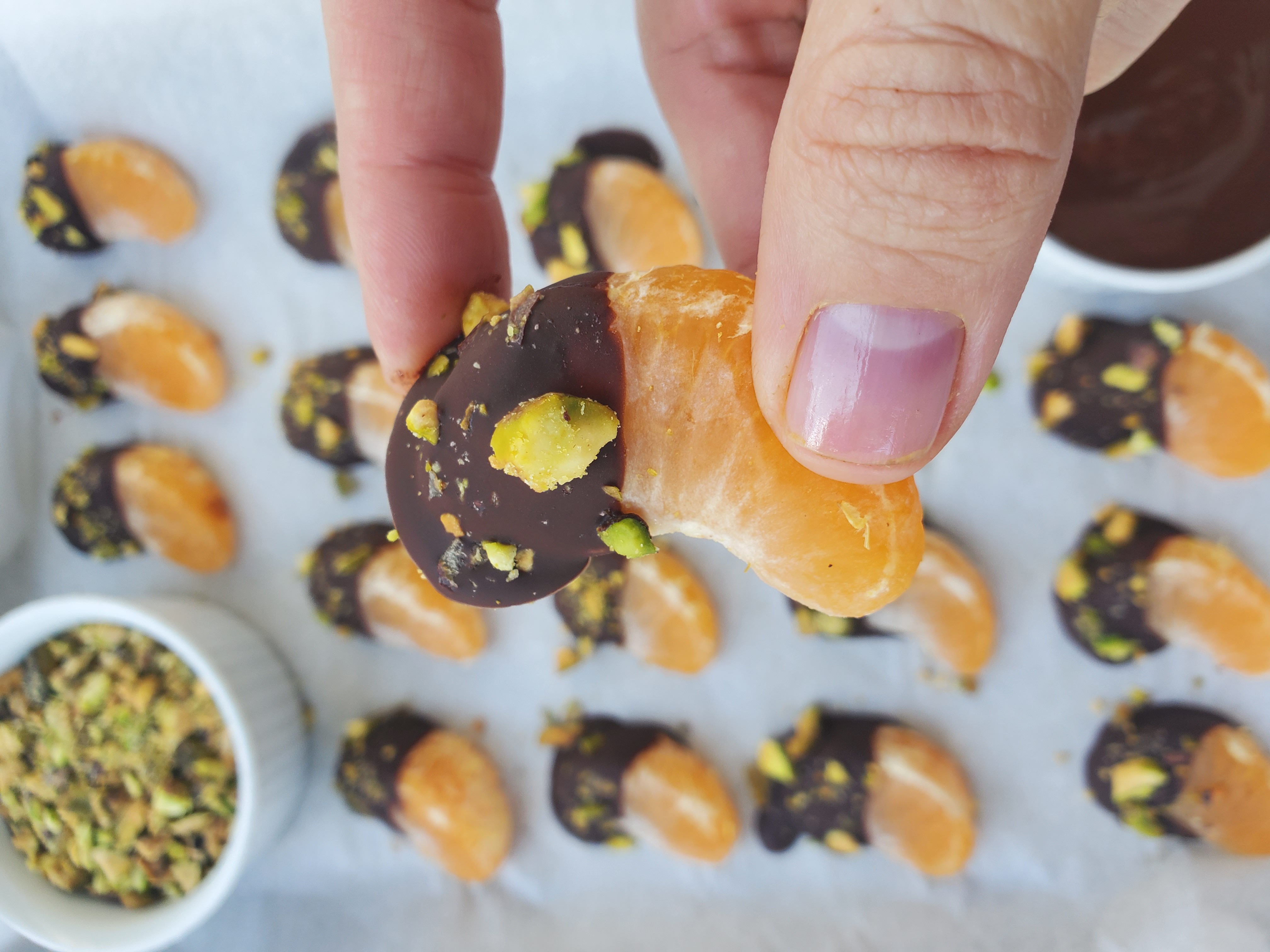 Hand holding a dark chocolate dipped mandarin close-up