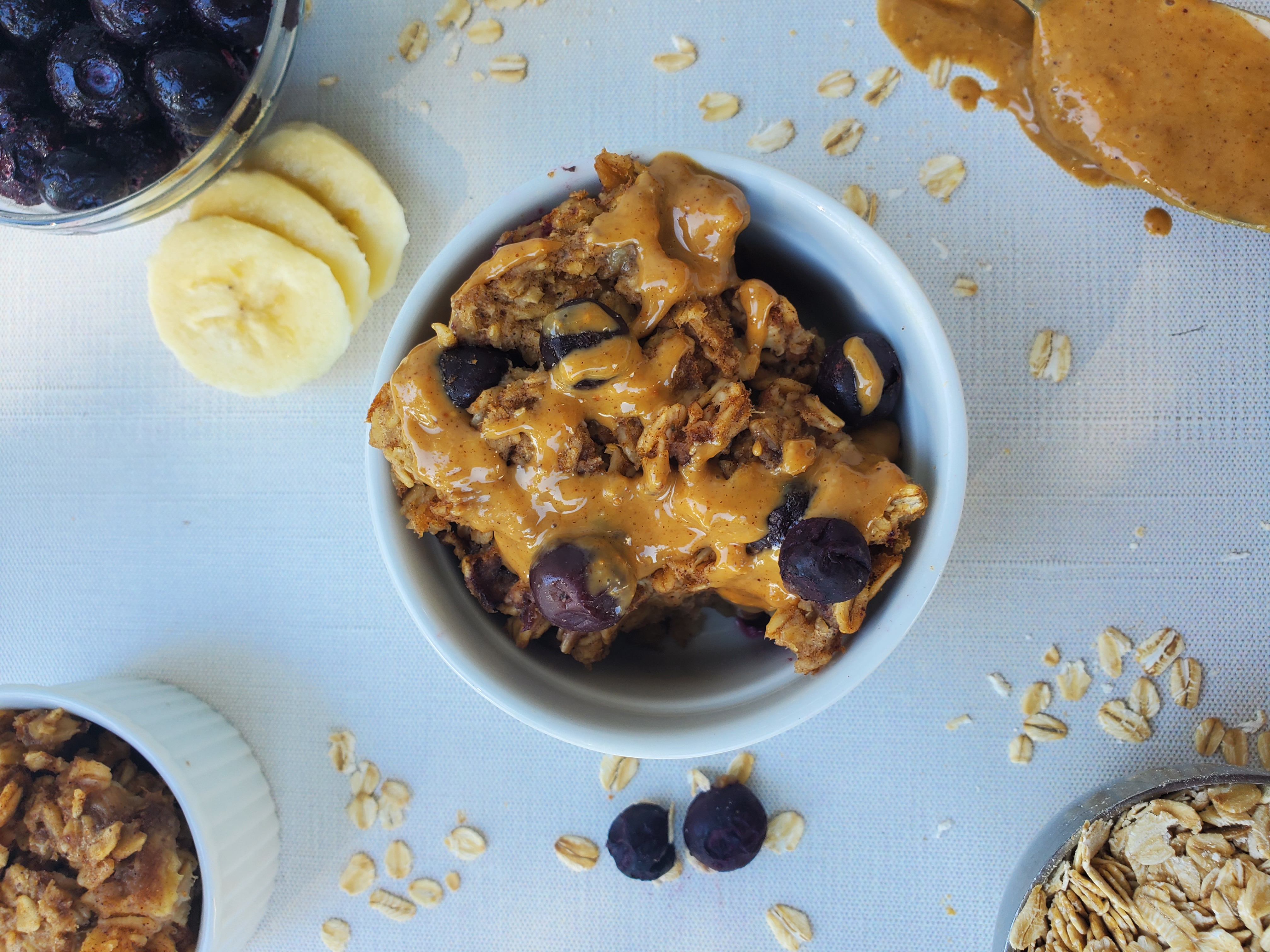 Baked Blueberry Oatmeal in a ramekin with peanut butter drizzled on top