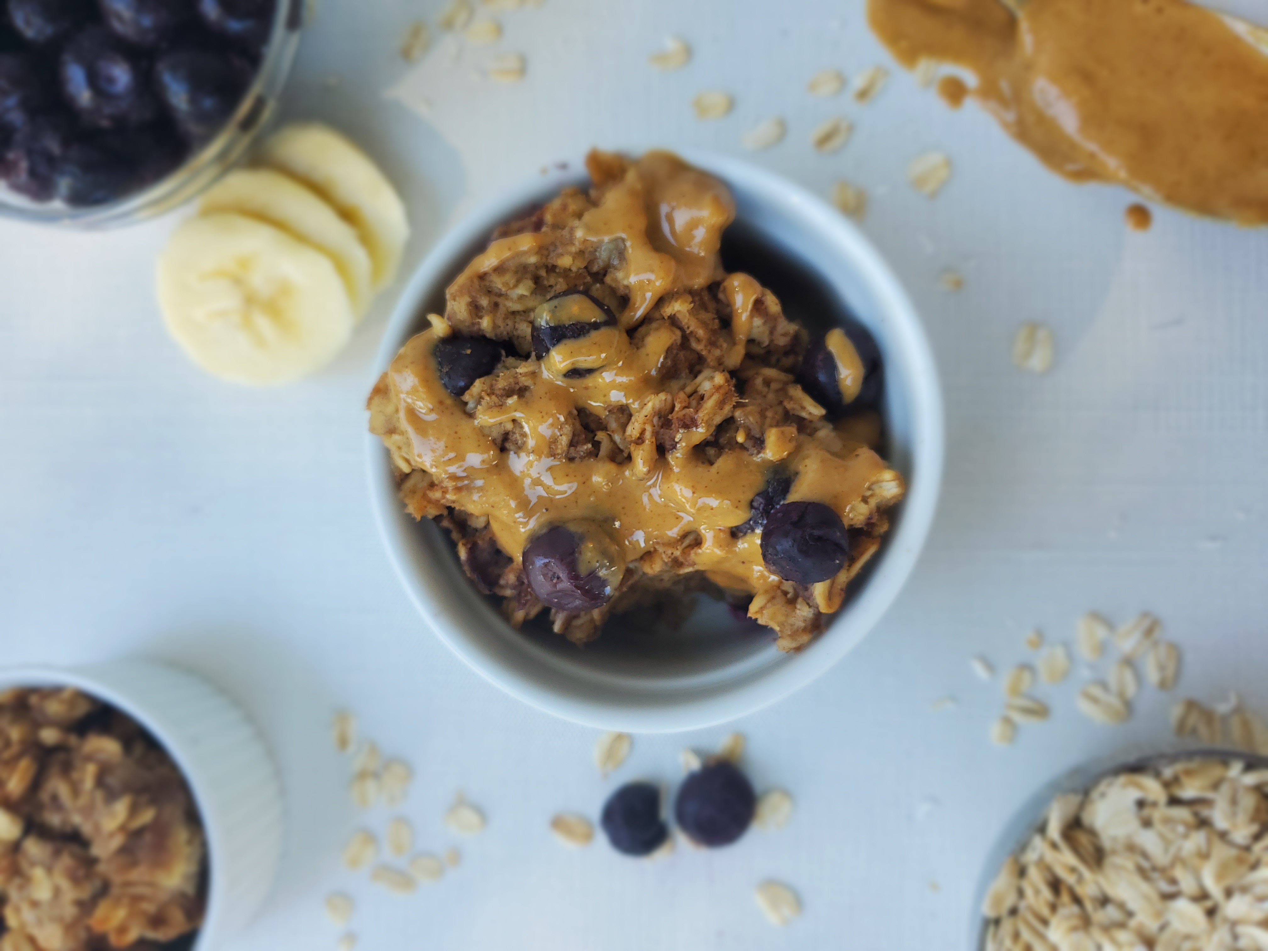 Baked Blueberry Oatmeal in a ramekin with peanut butter drizzled on top