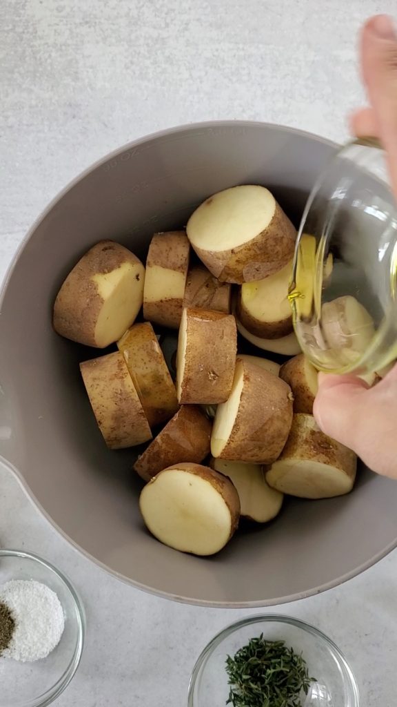 Potato discs in a large bowl adding olive oil