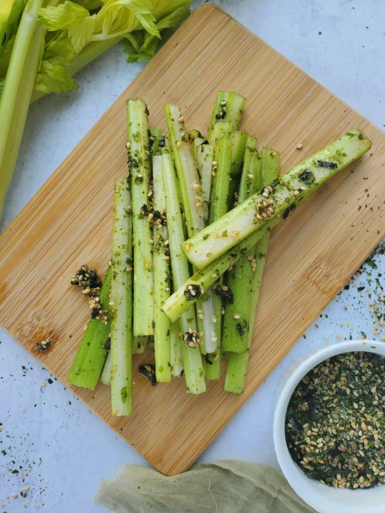 Celery on a cutting board drizzled with furikake seasoning