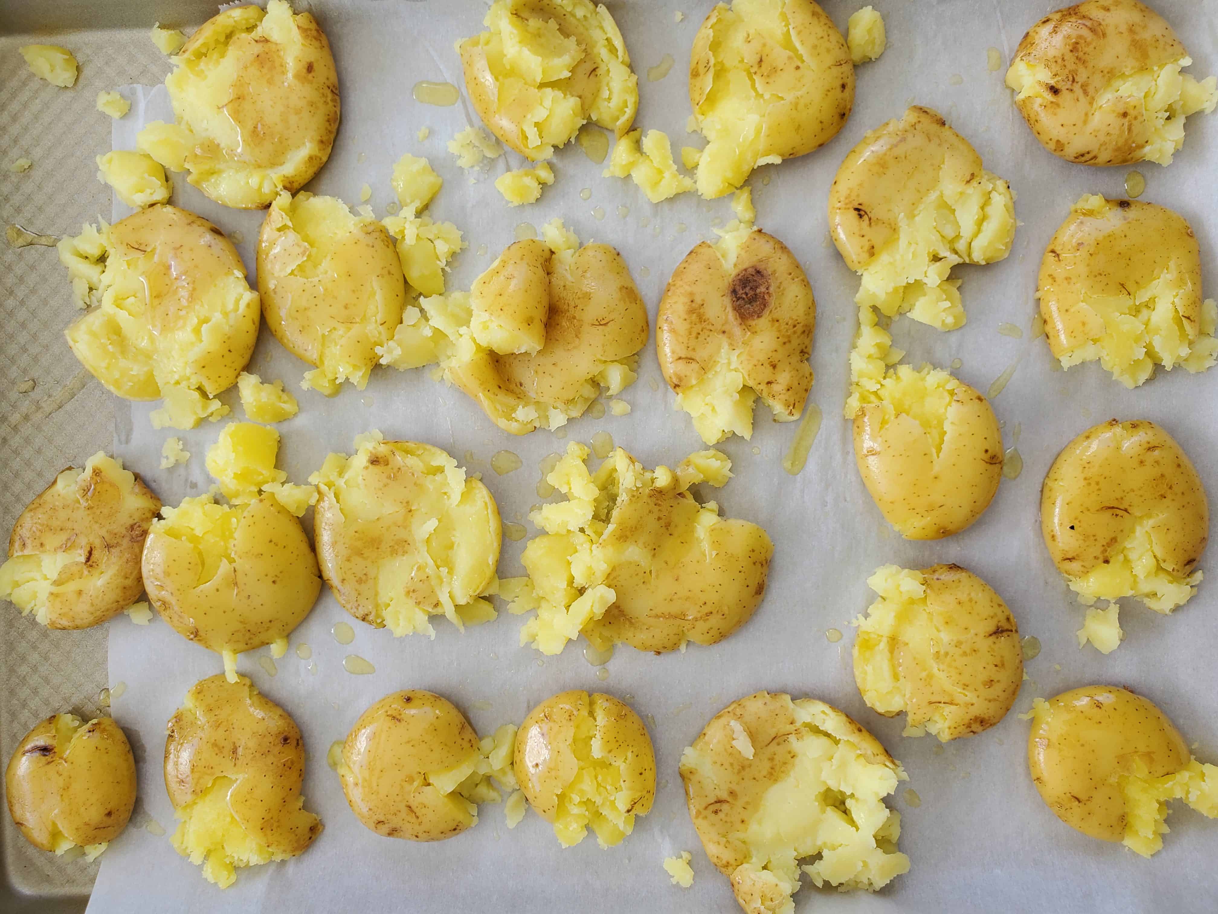 petite potatoes smashed on a baking sheet