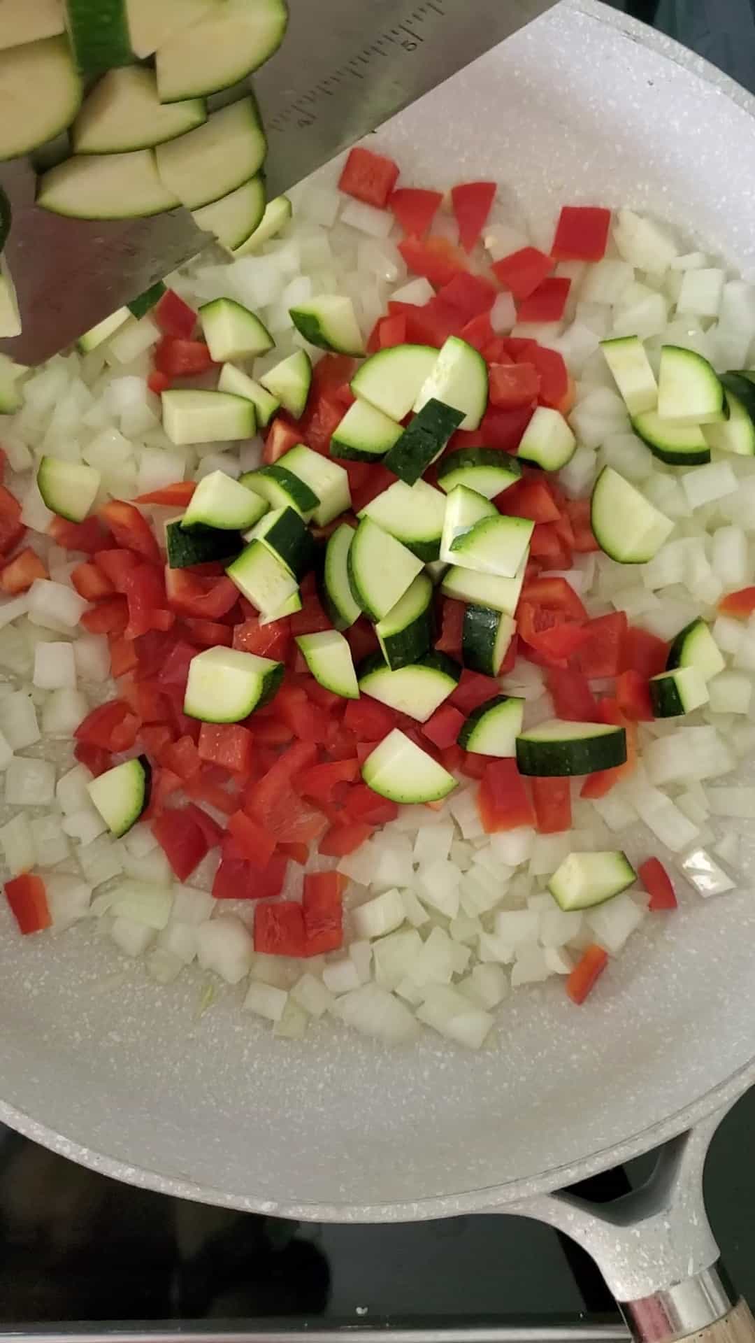 diced onions, red pepper, and zucchini sauteeing