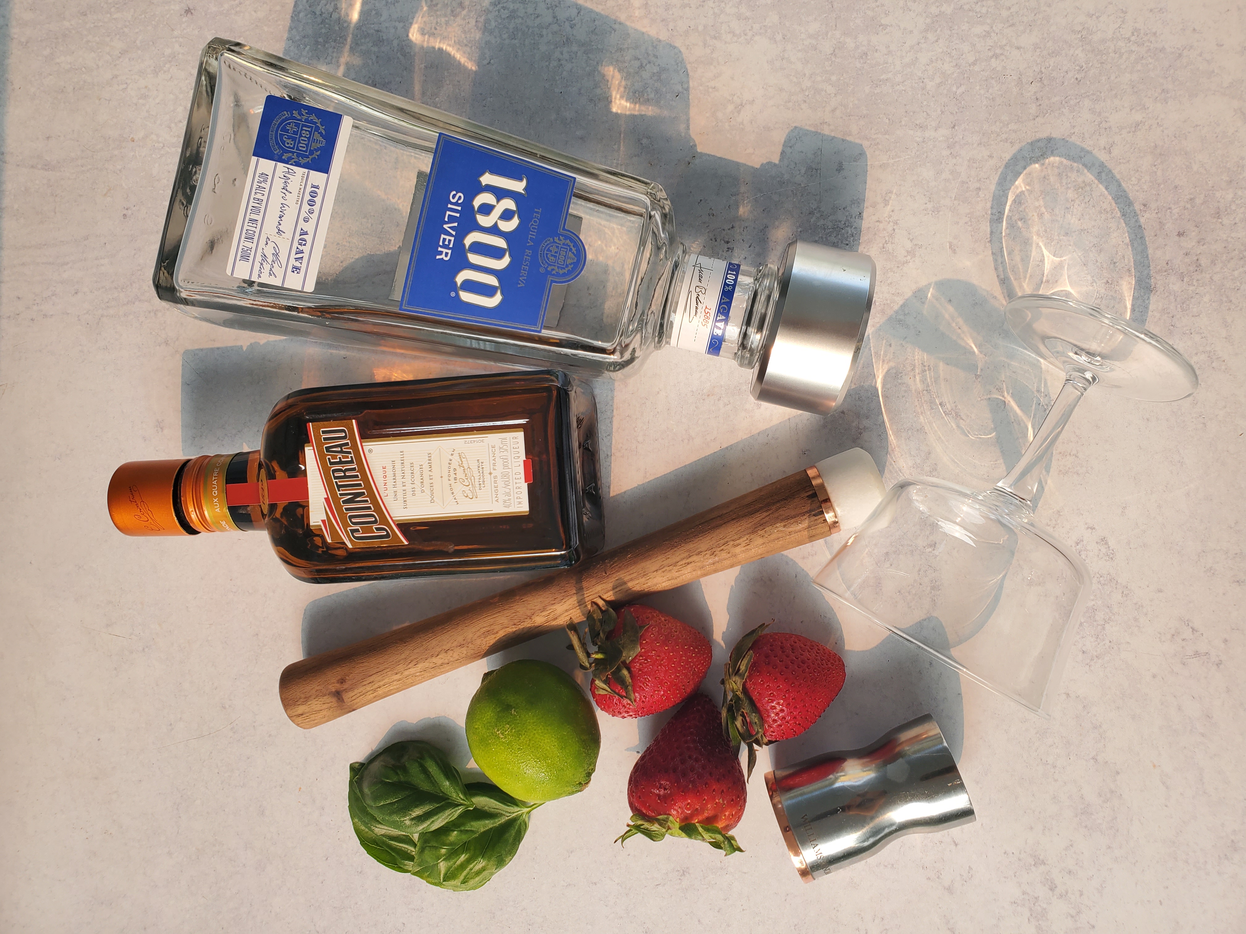 ingredients for a strawberry basil margarita:  tequila, cointreau, limes, basil, strawberries