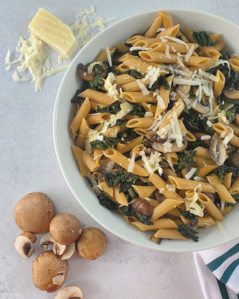 one-pot pasta set in a bowl with a towel, parmesan cheese, and mushrooms as props