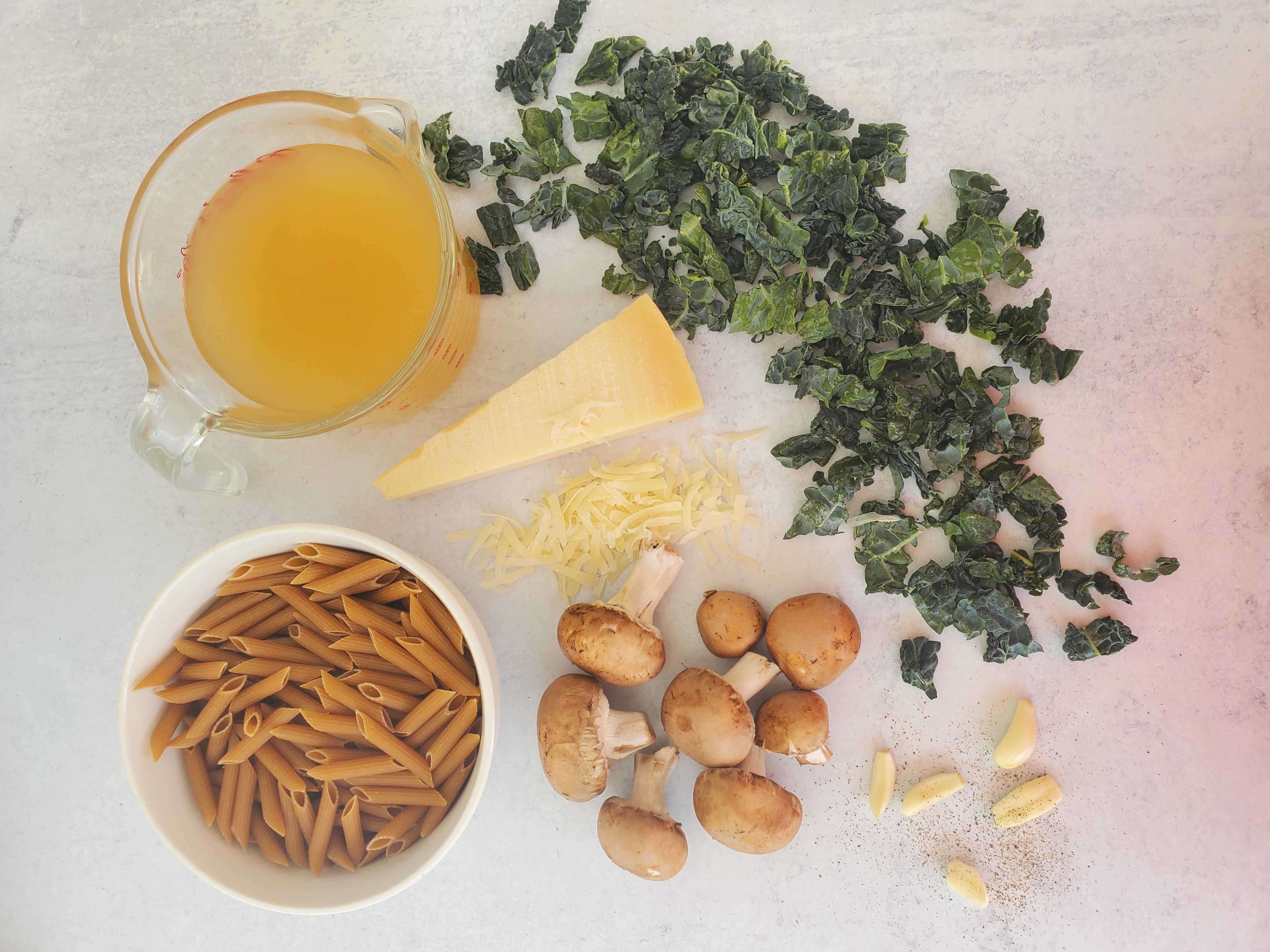 one-pot pasta ingredients: pasta, mushrooms, kale, broth, garlic, cheese