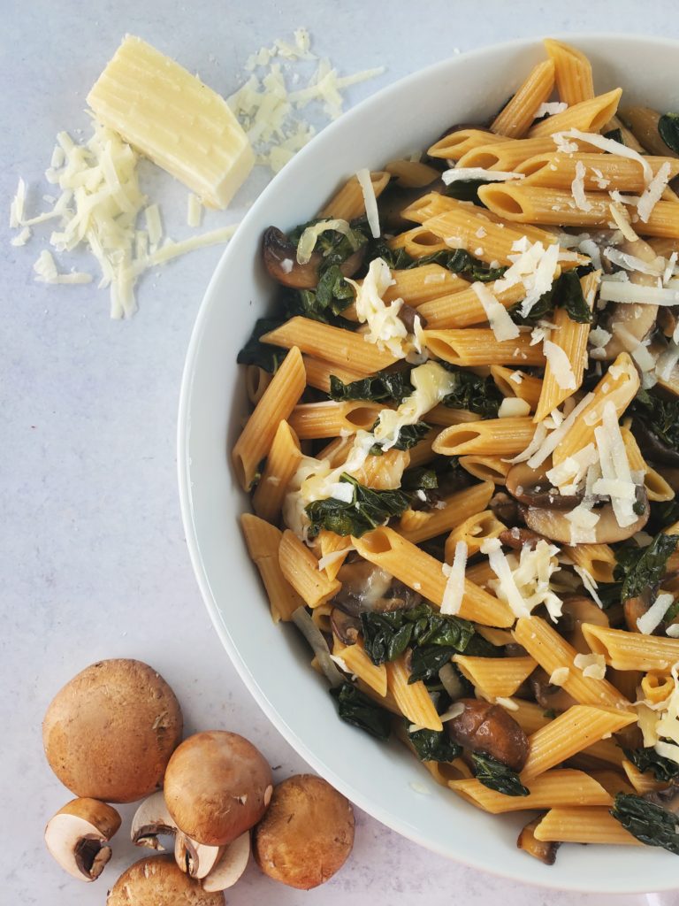 one-pot pasta in a bowl with mushrooms and parmesan cheese to the side as props