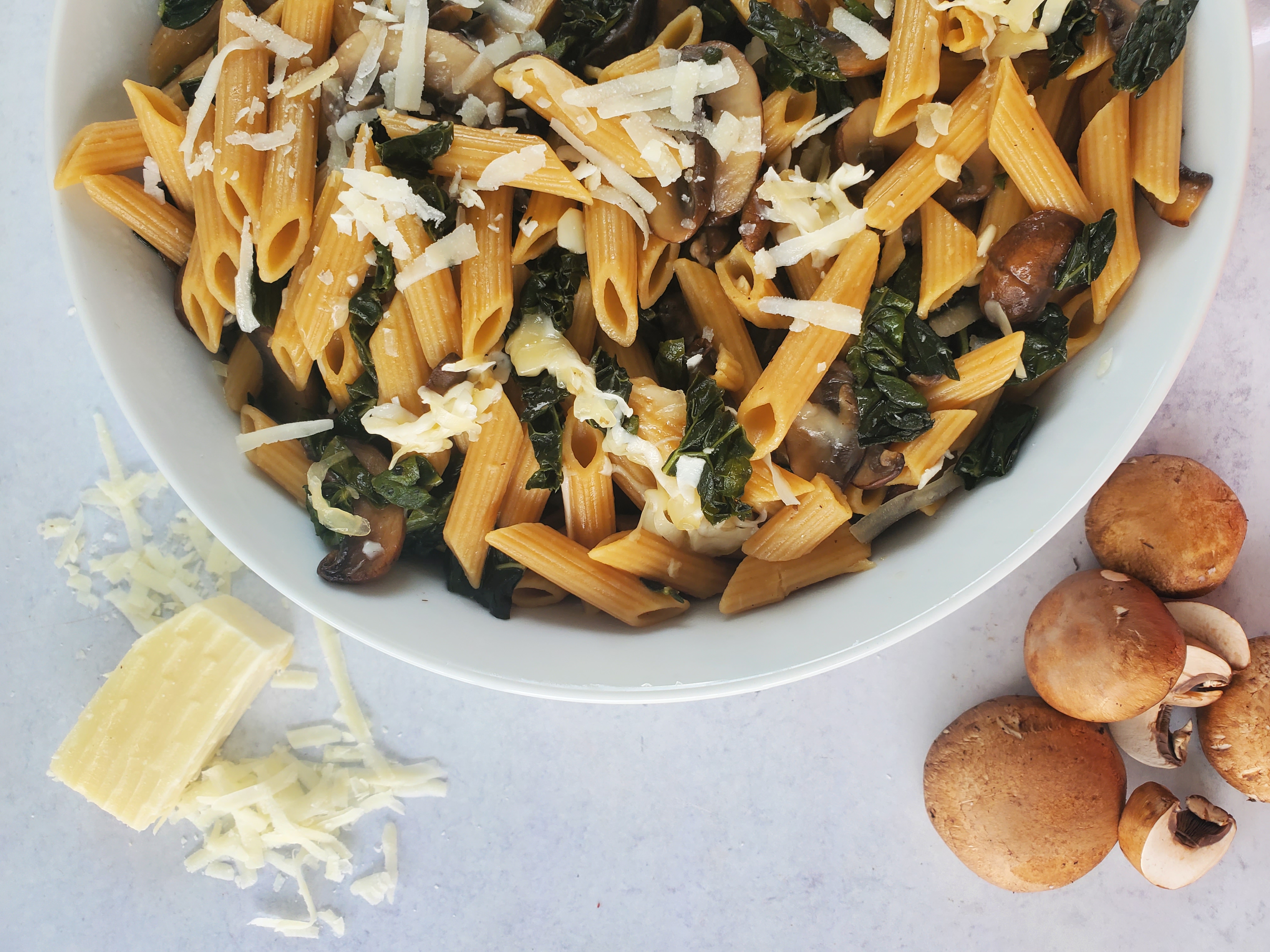 one-pot pasta in a bowl with mushrooms and parmesan cheese to the side as props