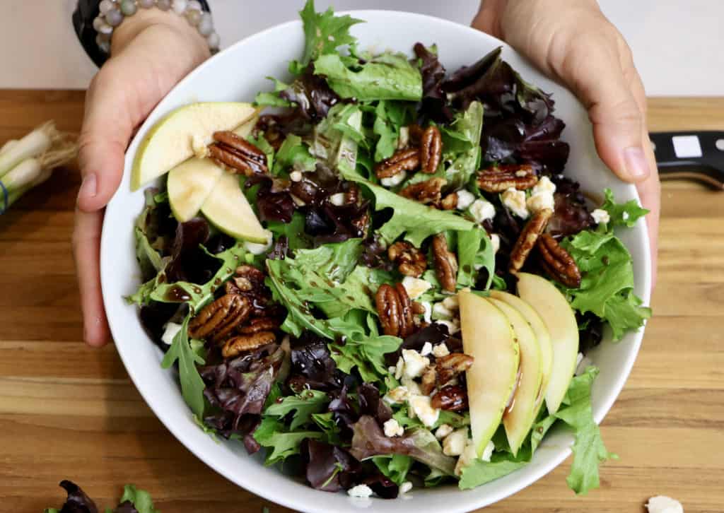 close up bowl of salad with maple glazed pecans, feta, and pears with mixed greens