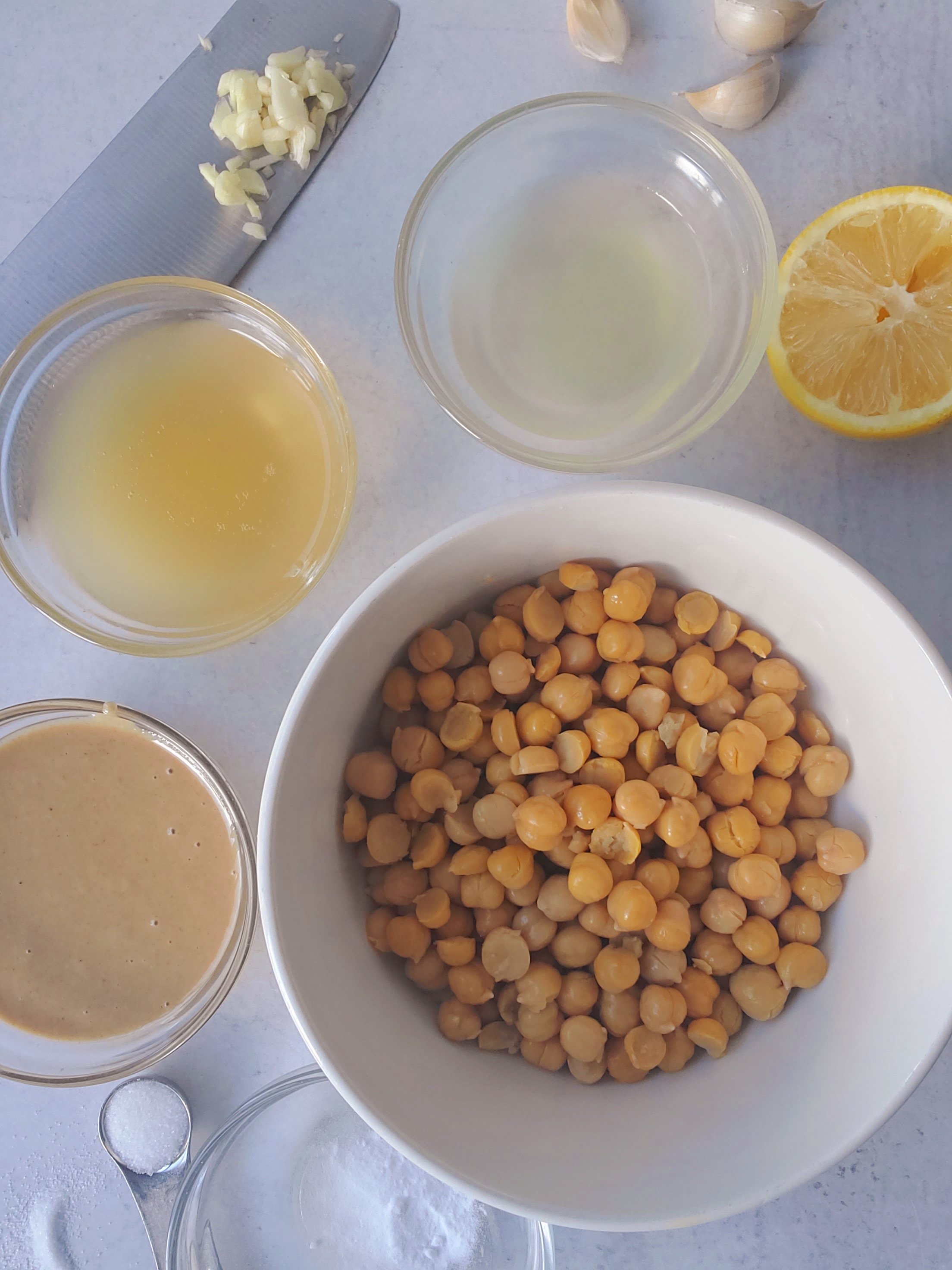 Ingredients for homemade hummus - chickpeas, lemon juice, tahini, garlic, cold water or chickpea reserved liquid
