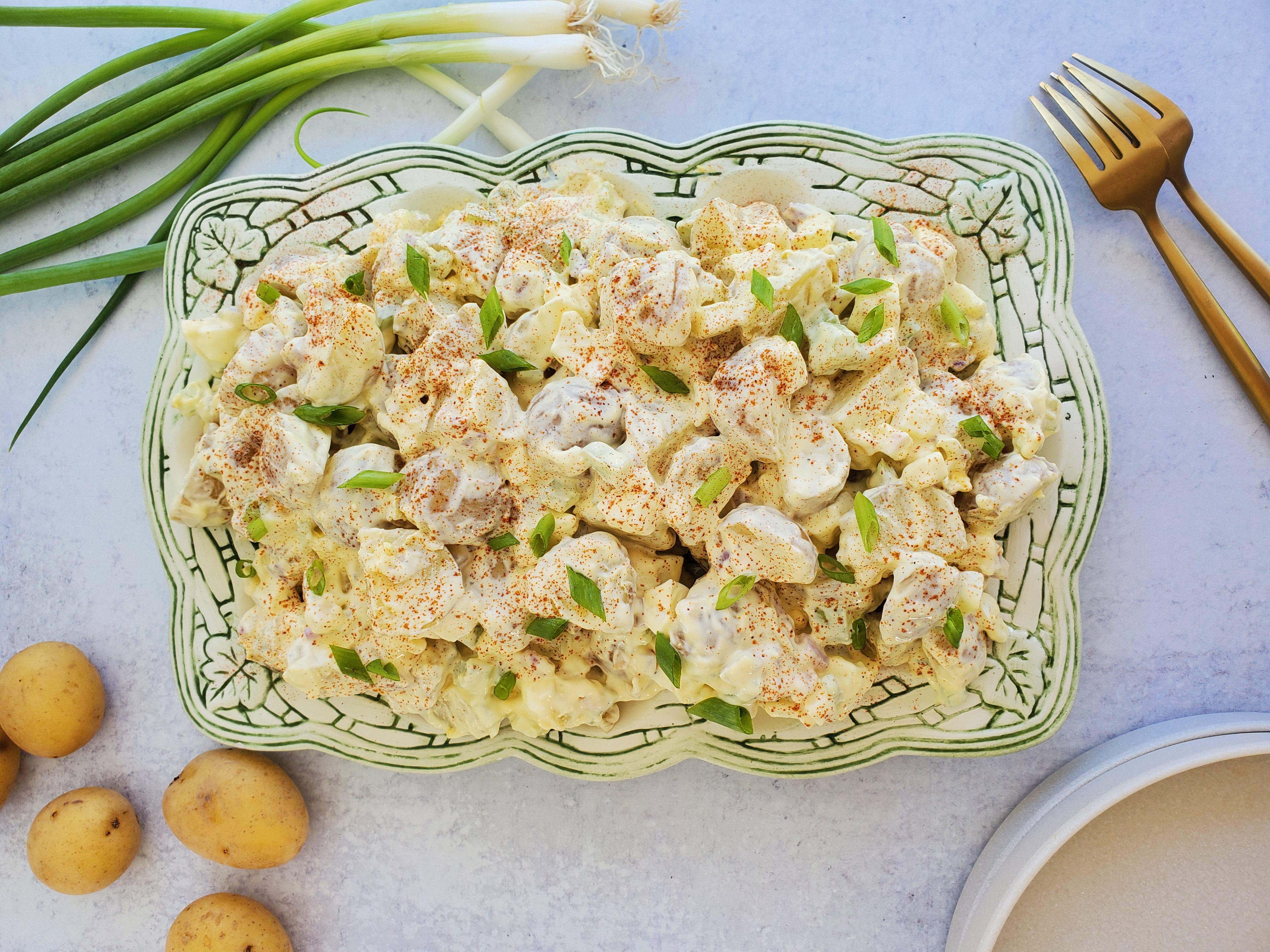 Egg Potato Salad plated and ready to serve with plates and forks to the side