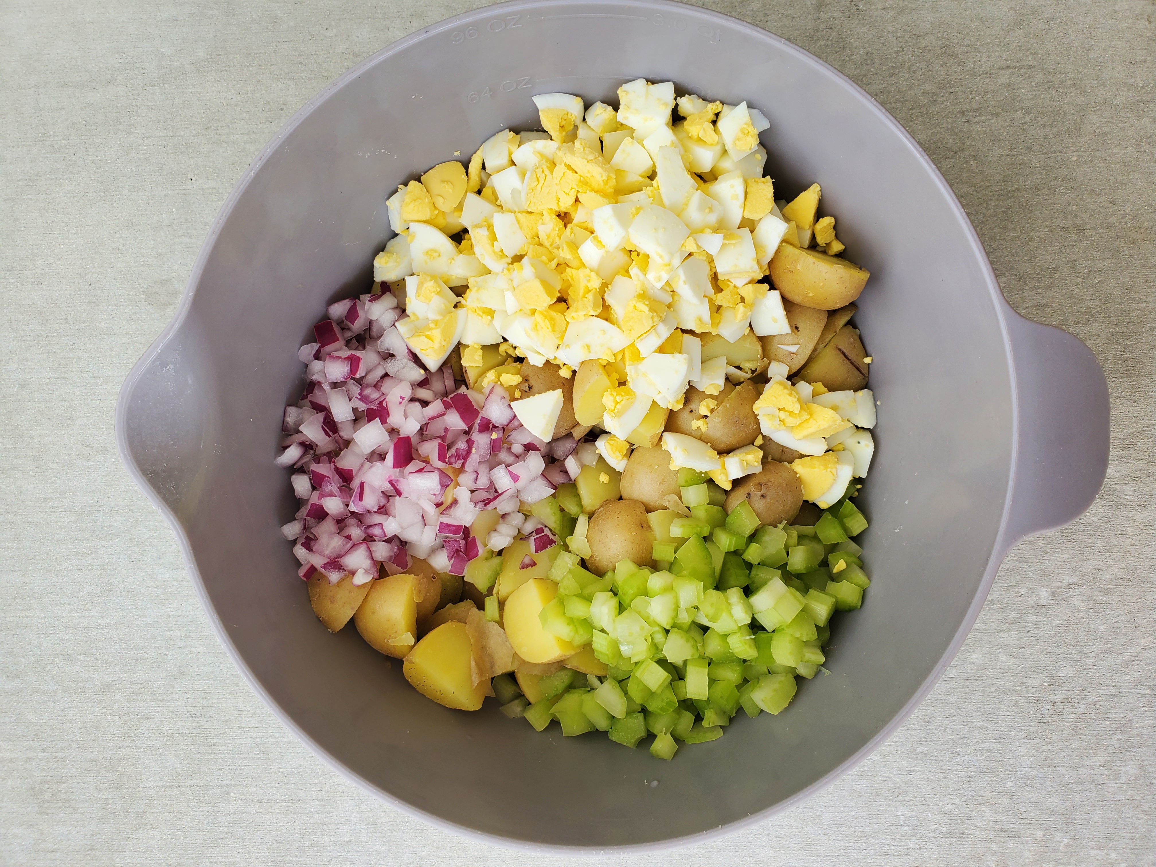 one bowl with egg potato salad ingredients - hard-boiled egg, potatoes, celery, onion