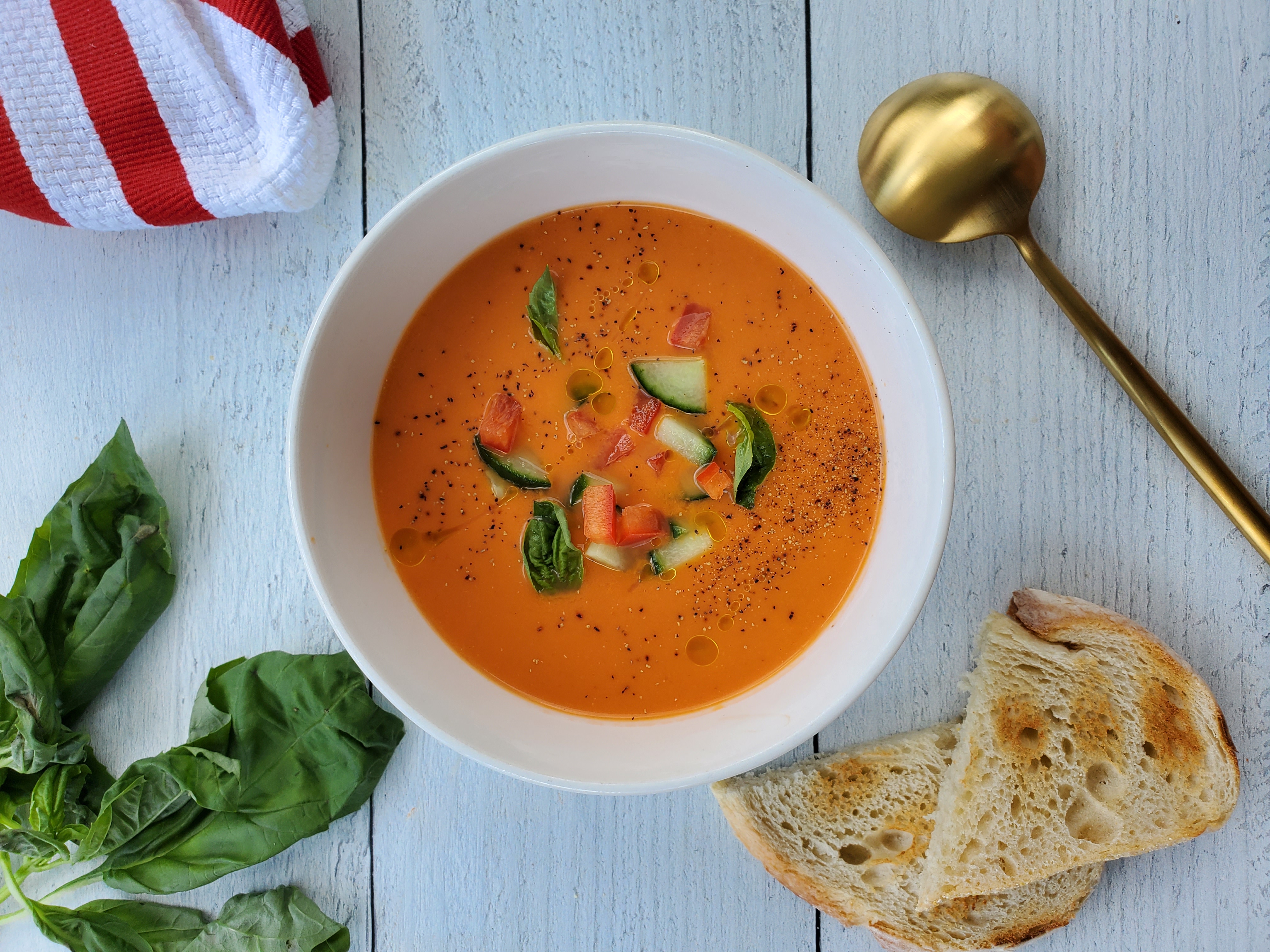 Bowl of gazpacho with sourdough bread and a spoon