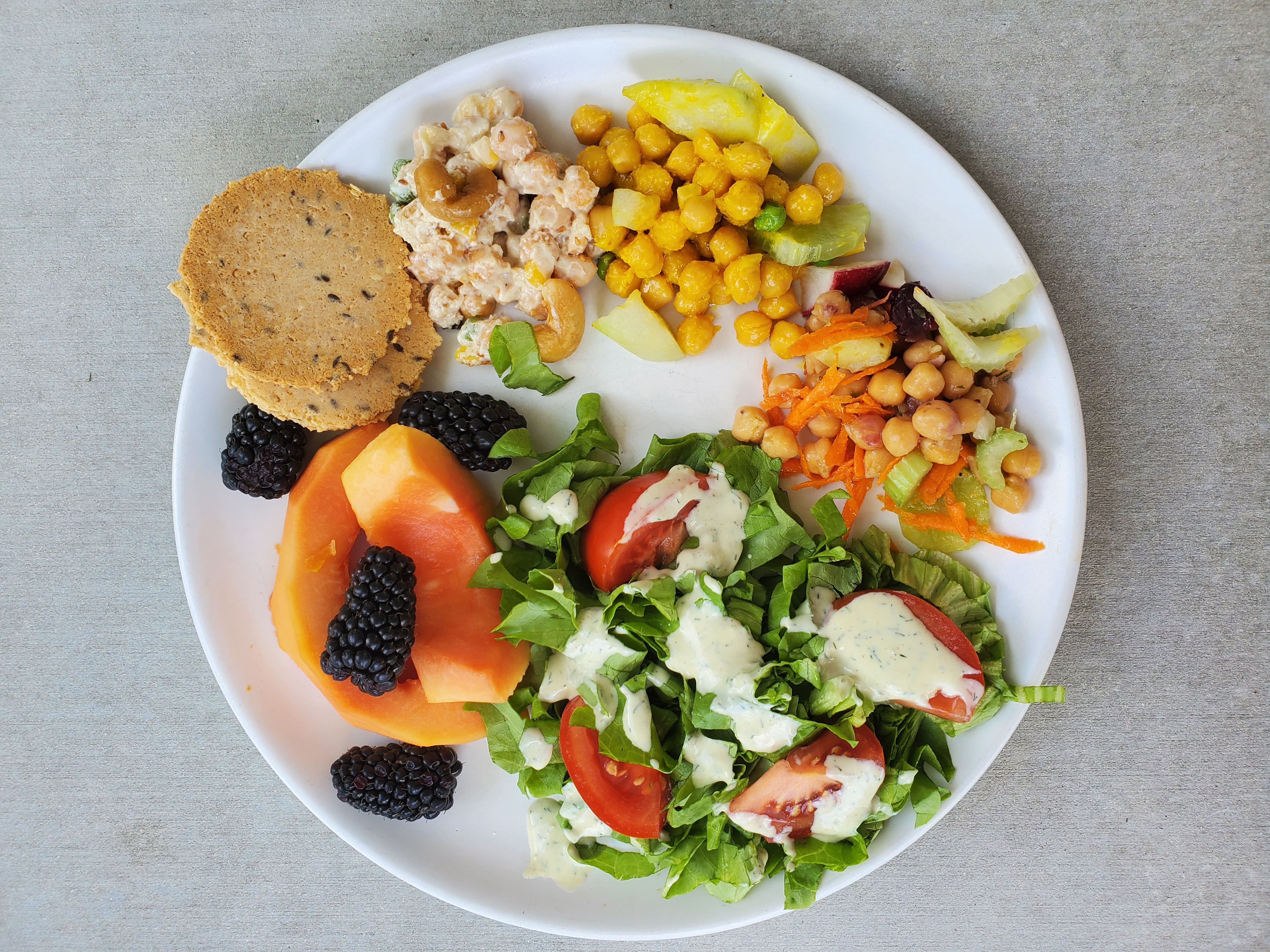 Plate of chickpea salads, fruit, salad, and crackers