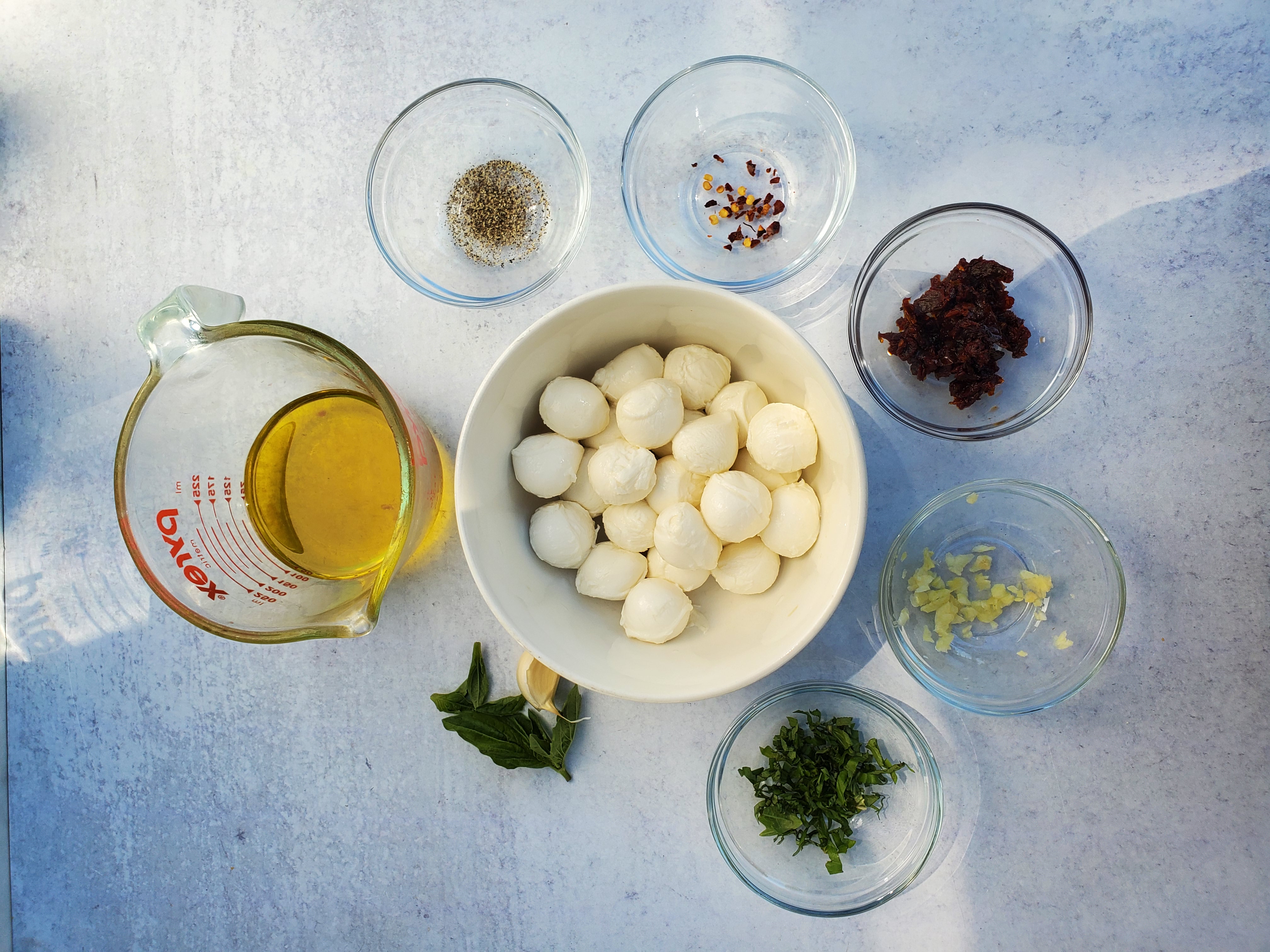 mozzarella balls, olive oil, sun-dried tomatoes, garlic, basil, black pepper