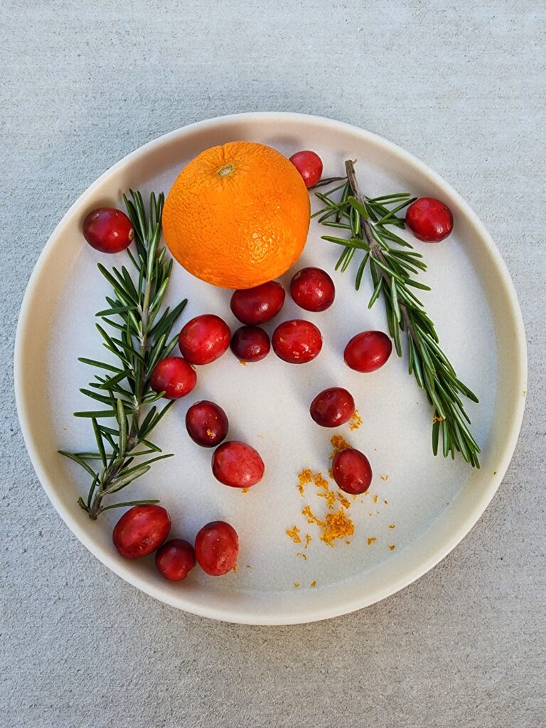 Plate of cranberries, orange, orange zest, rosemary