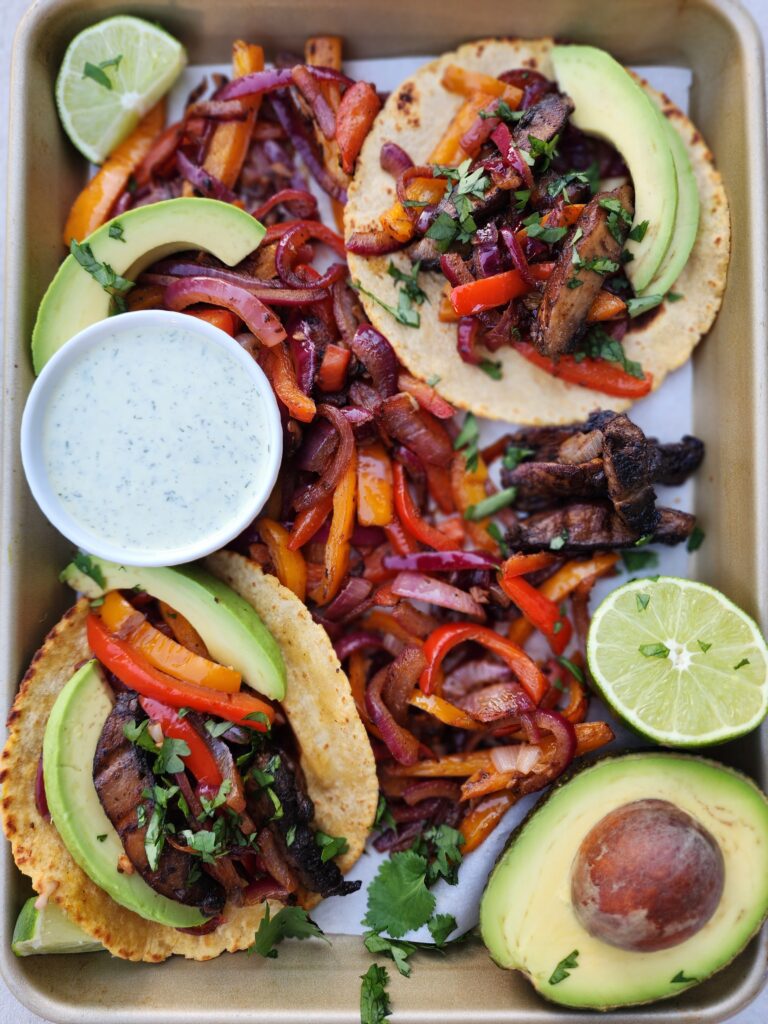 Sheet Pan with peppers, onions, portobello mushrooms, tortillas, limes, avocado slices to fix Portobello Fajitas