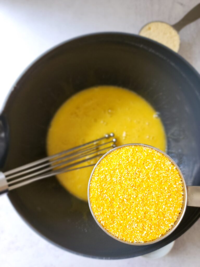 Cornmeal being added to a bowl for olive oil cake