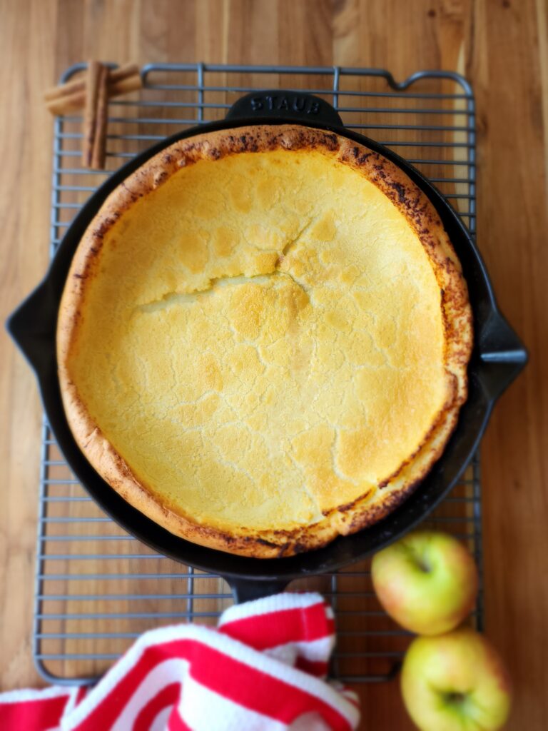 Blender Dutch Baby in a cast-iron skillet on a wood cutting board