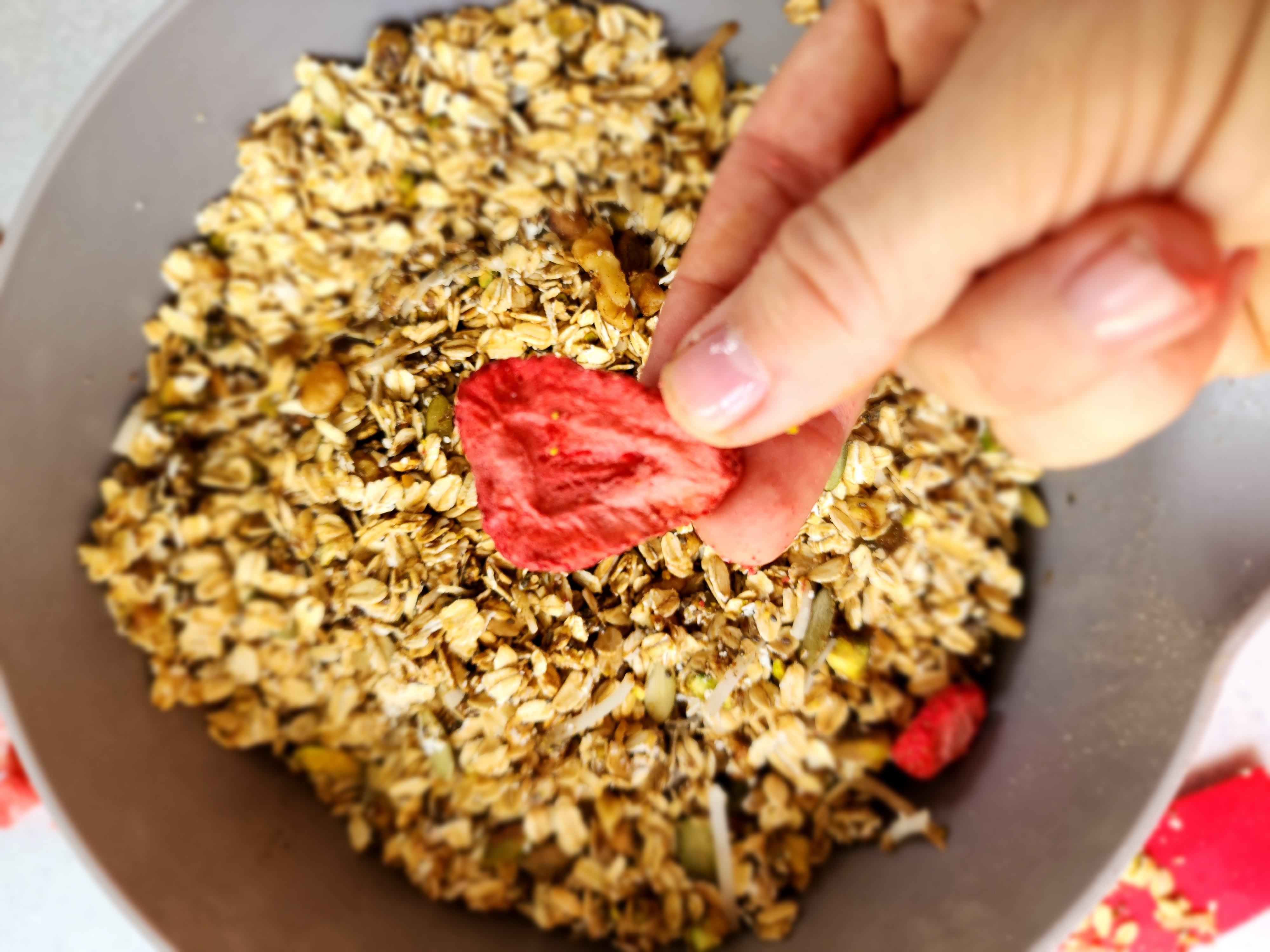 Bowl of all the ingredients for Homemade Muesli with a freeze-dried strawberry