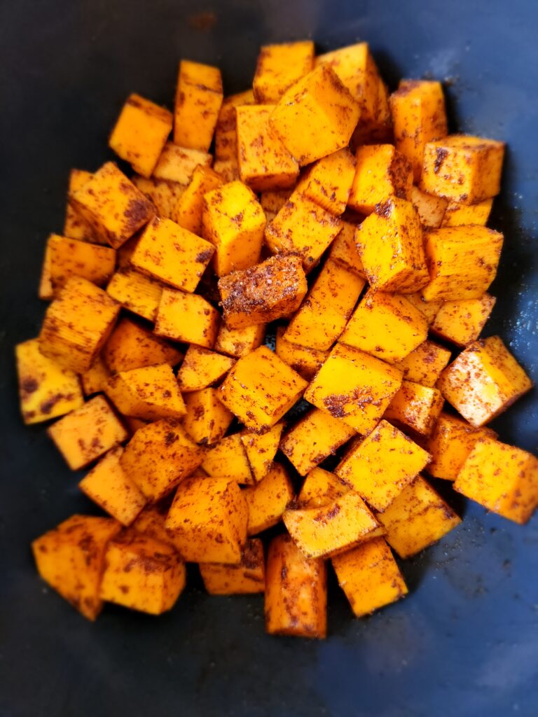 Butternut Squash cut up in cubes with spices in a bowl
